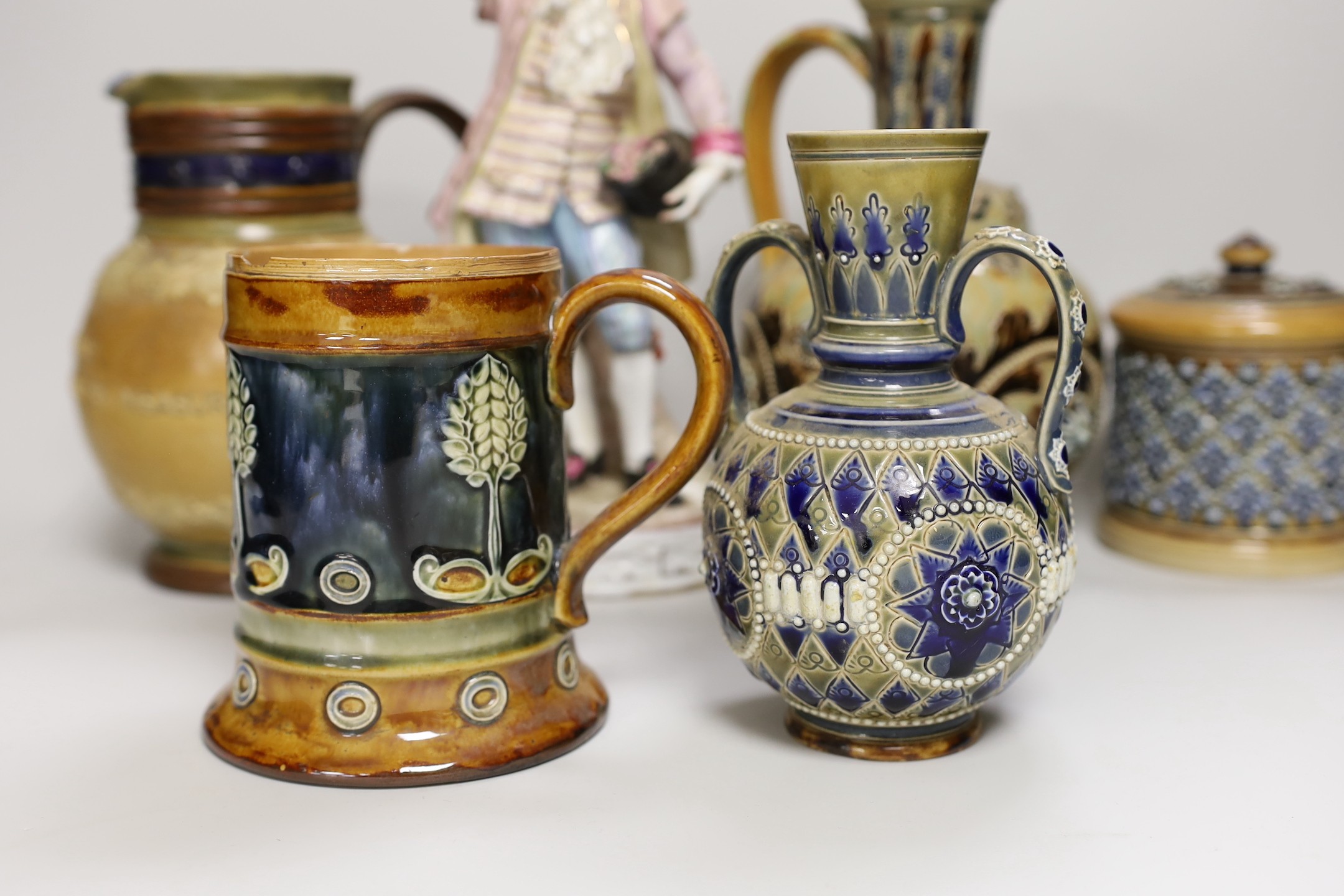 A group of six Doulton Lambeth stoneware vessels, tallest 22.5 cm and a French porcelain figure of a gentleman (7)